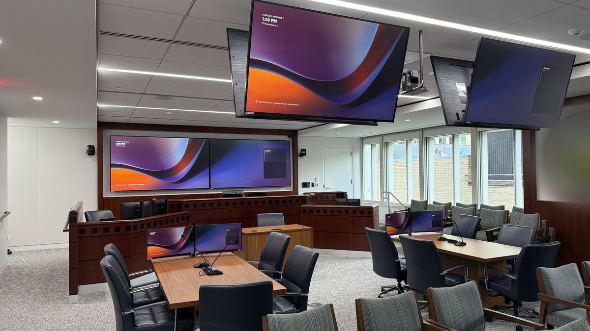 Government hearing room with a dual video wall, ceiling-hung monitors, and integrated dais control, by Enlightened Audiovisual