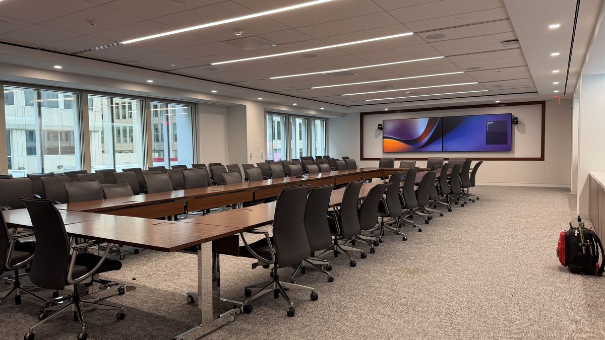 Long executive boardroom with dual ultra-wide video conferencing displays, designed and installed by Enlightened Audiovisual